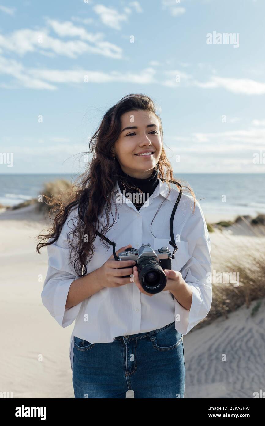 Jeune femme souriante avec un appareil photo à la plage Banque D'Images