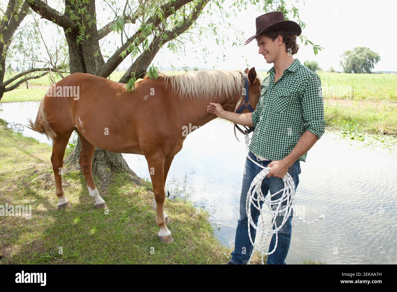 Homme debout avec un cheval près d'un étang Banque D'Images