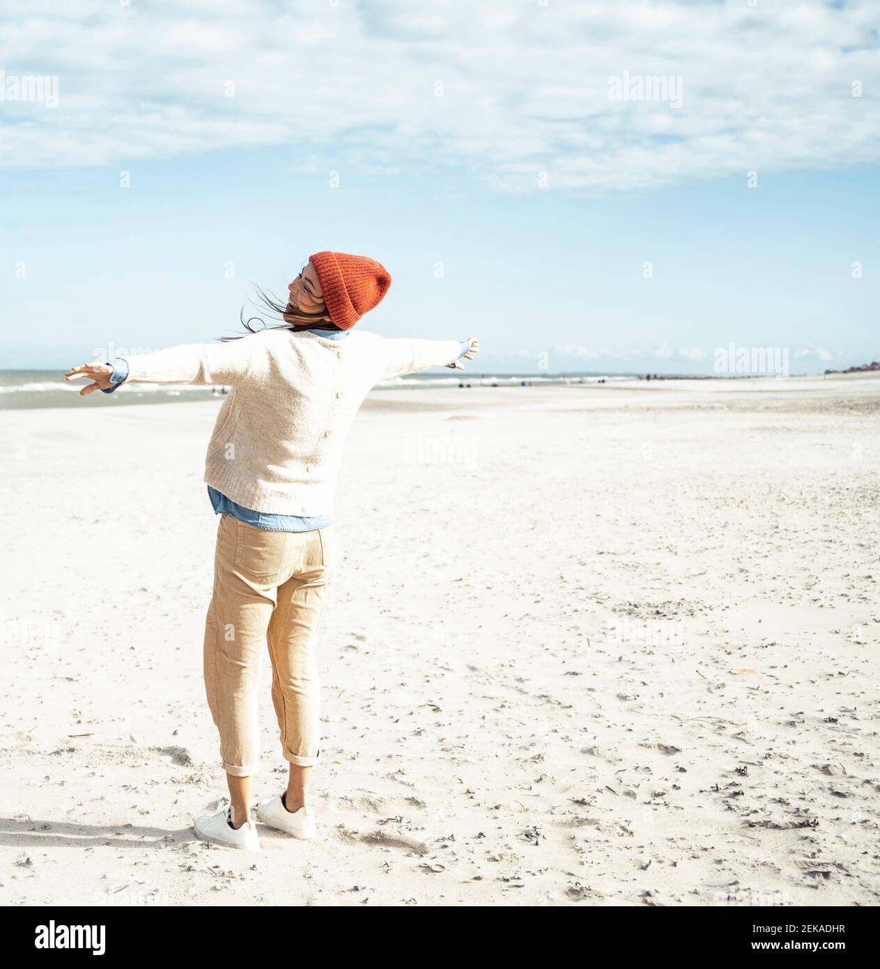 Jeune femme debout sur une plage de sable avec des bras levés Banque D'Images