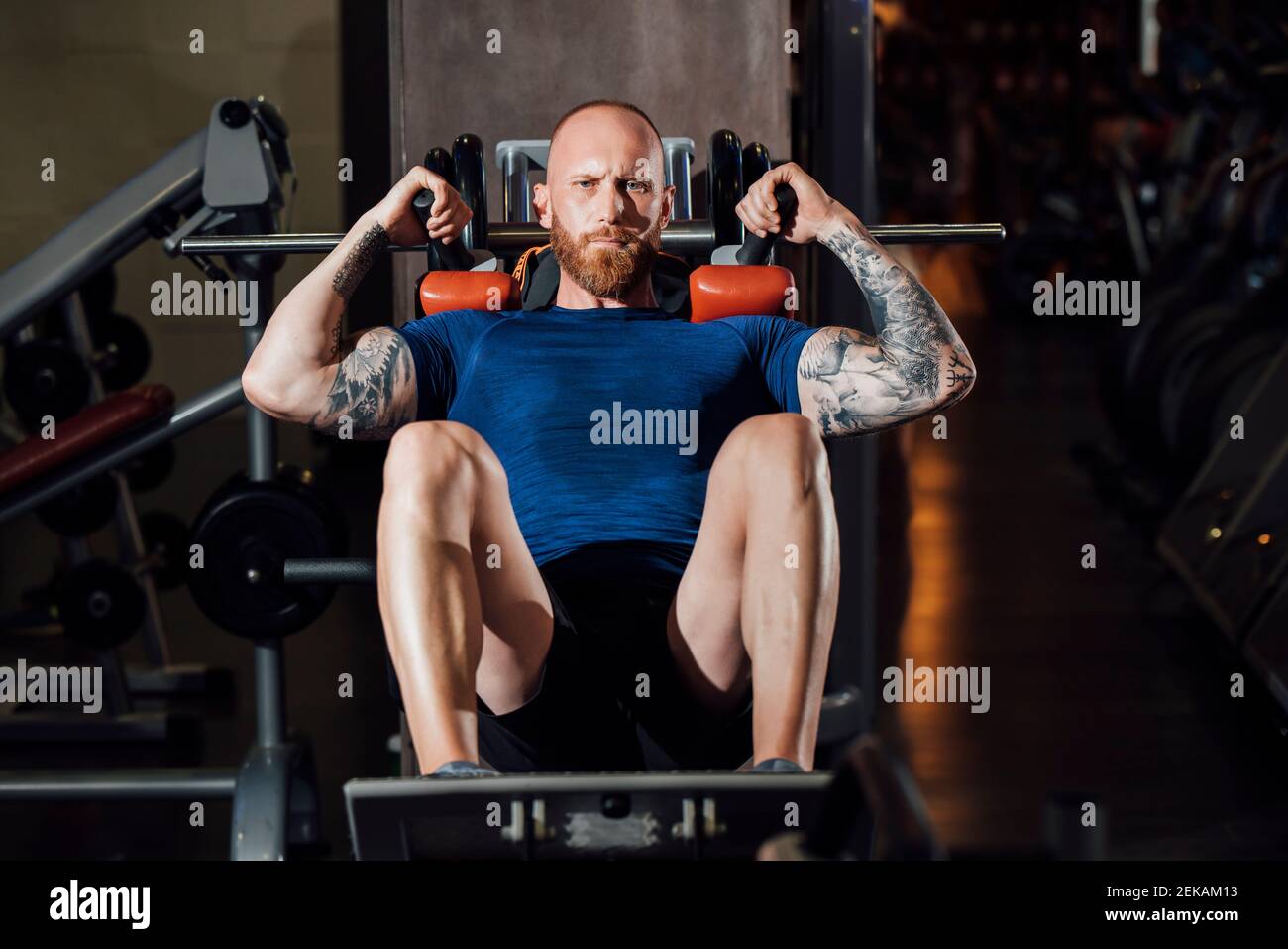 Homme faisant de l'exercice quadriceps sur la machine de squat de hack à la salle de gym Banque D'Images