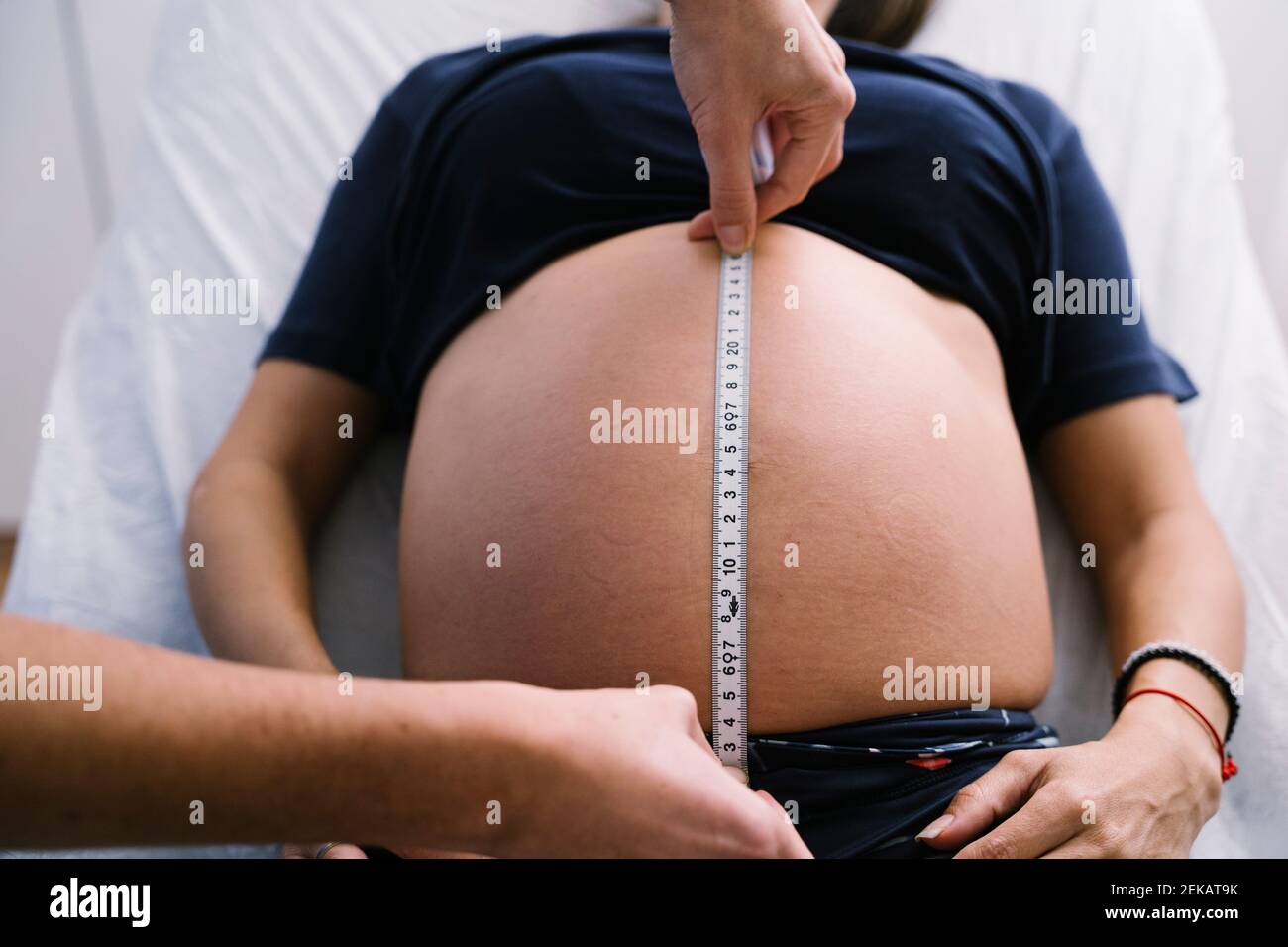 Infirmière de sexe féminin mesurant l'abdomen de la femme enceinte à l'aide d'un ruban de mesure Banque D'Images