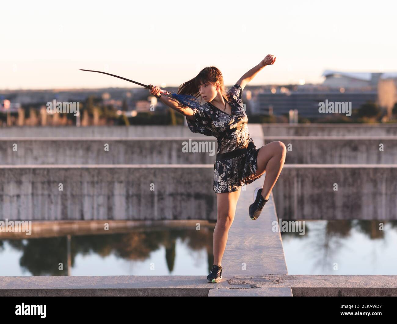 Athlète féminine pratiquant l'épée sur la structure contre le ciel clair à coucher de soleil Banque D'Images Athlète féminine pratiquant l'épée sur la structure contre le ciel clair à coucher de soleil Banque D'Images