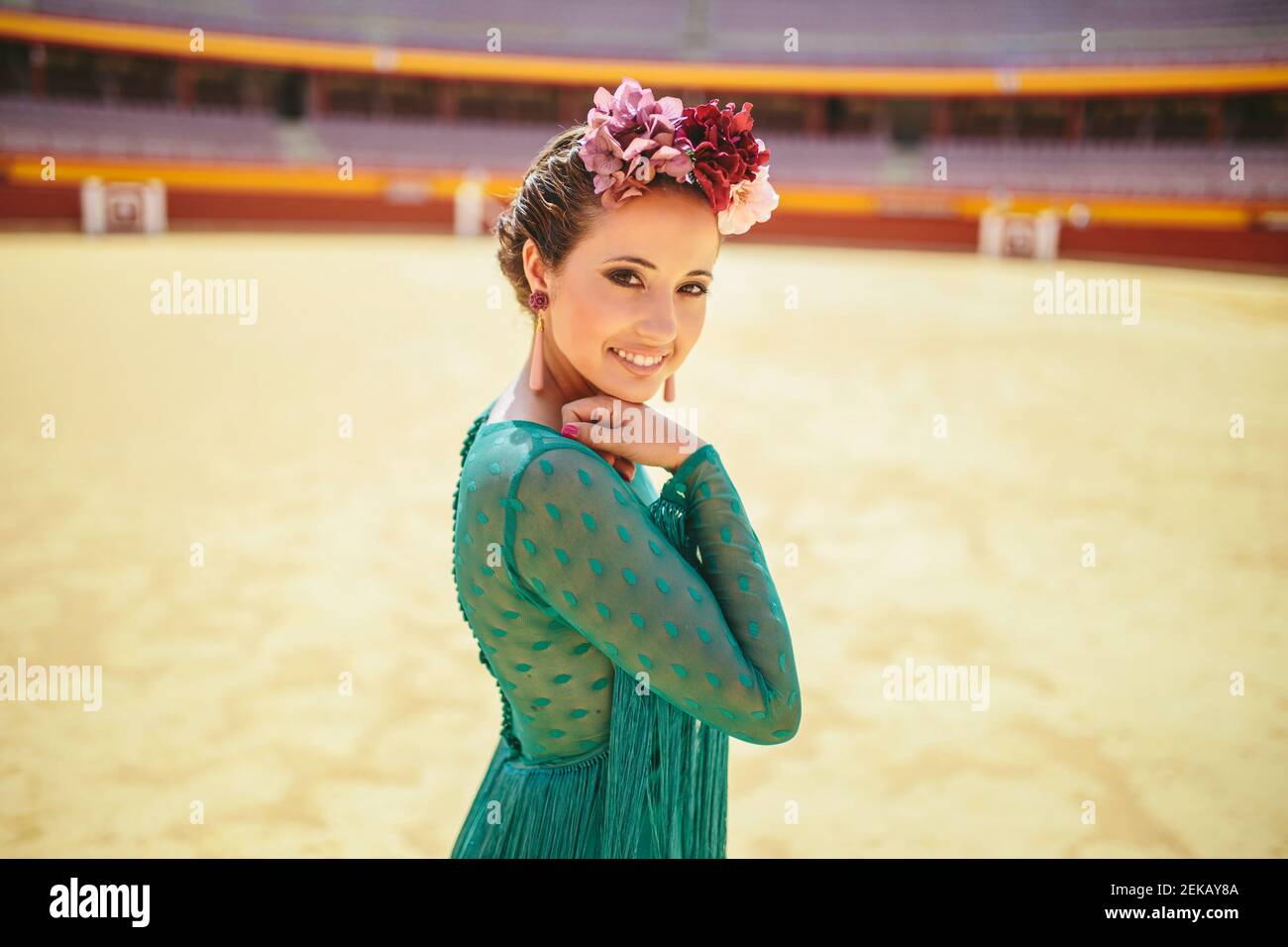 Danseur de flamenco souriant vêtu d'une robe bleue et de fleurs debout bullring Banque D'Images