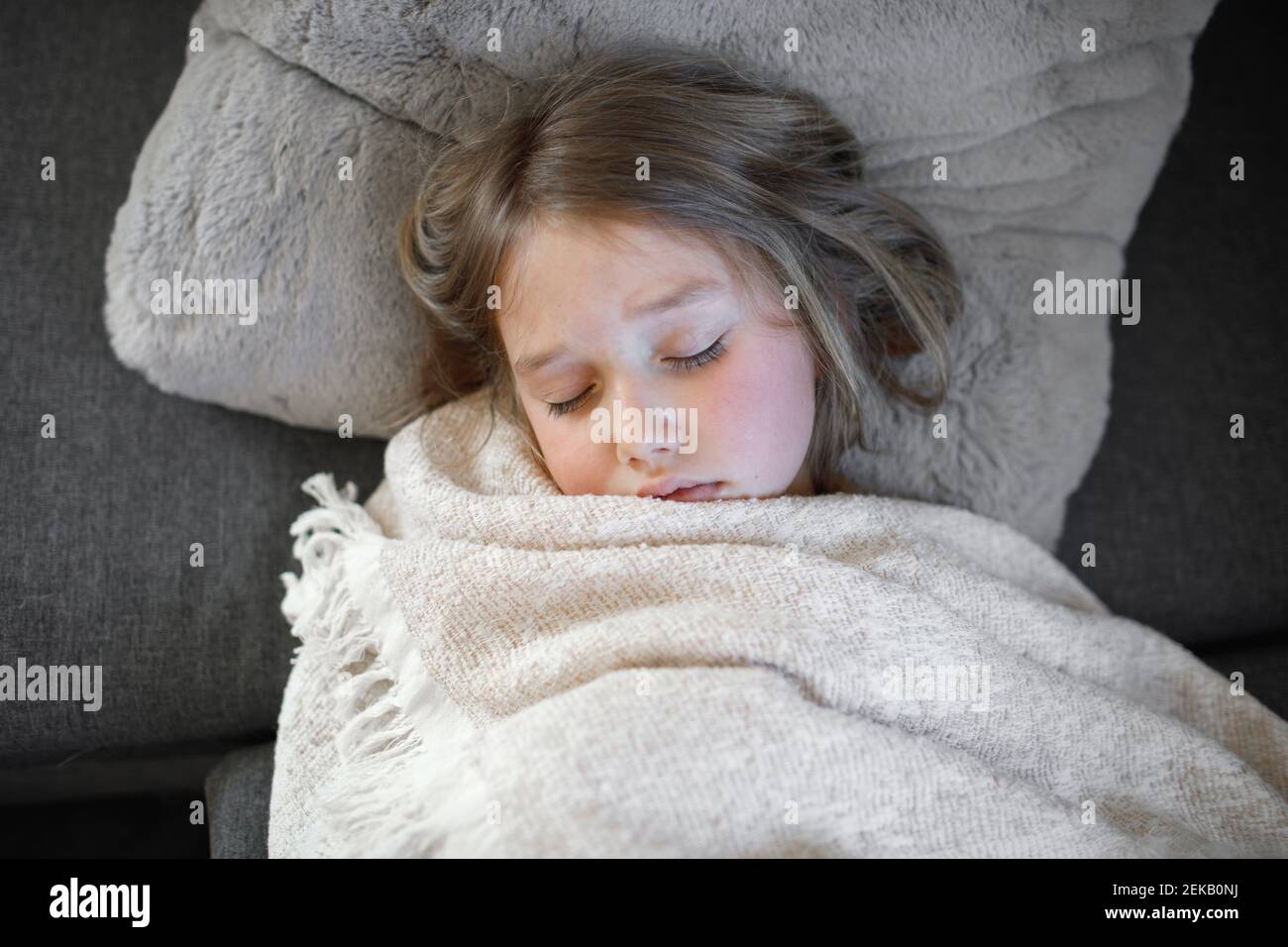 Fille malade dormant avec une couverture sur le canapé à la maison Banque D'Images