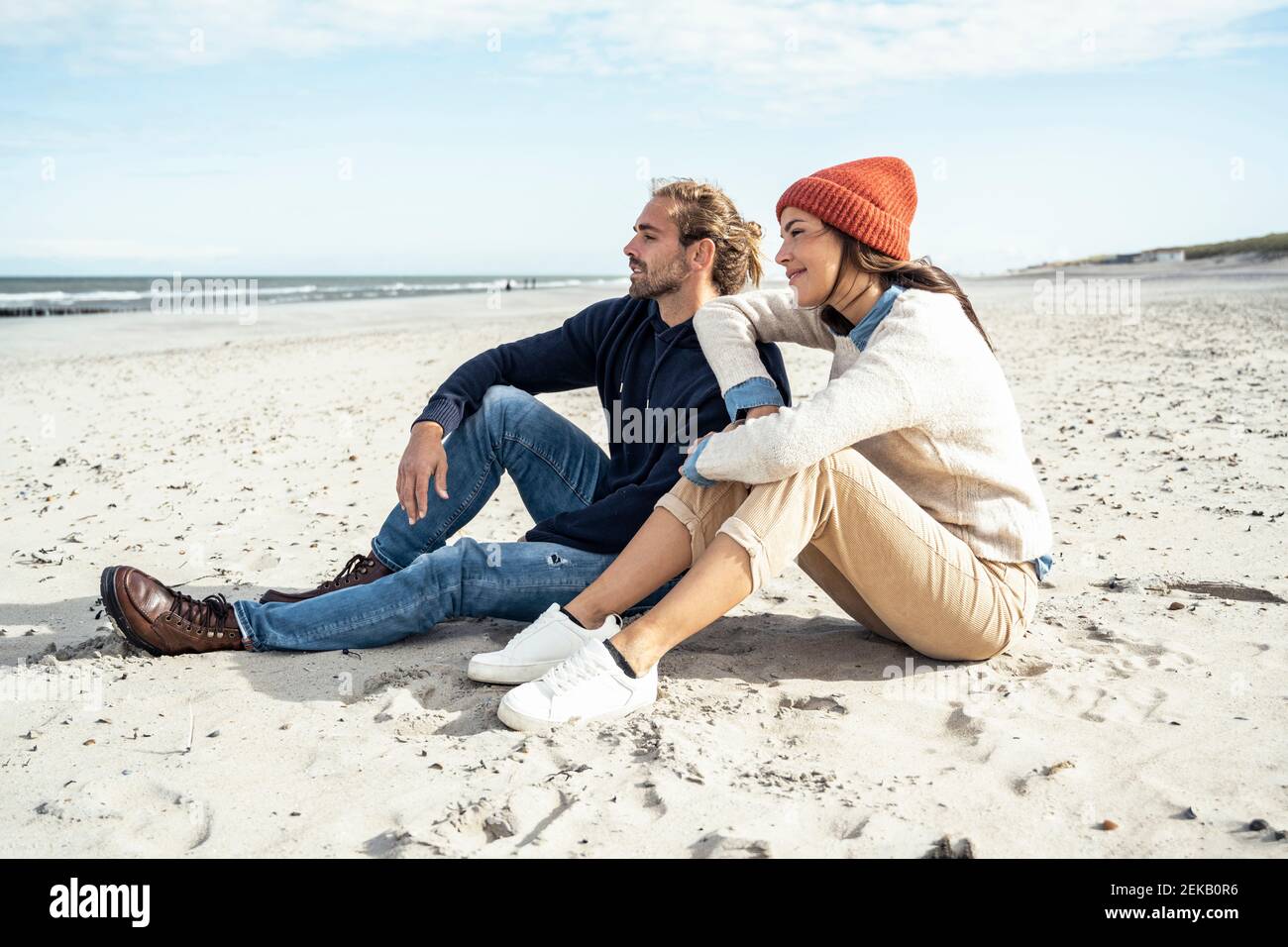 Jeune couple assis ensemble sur le sable de la plage Banque D'Images