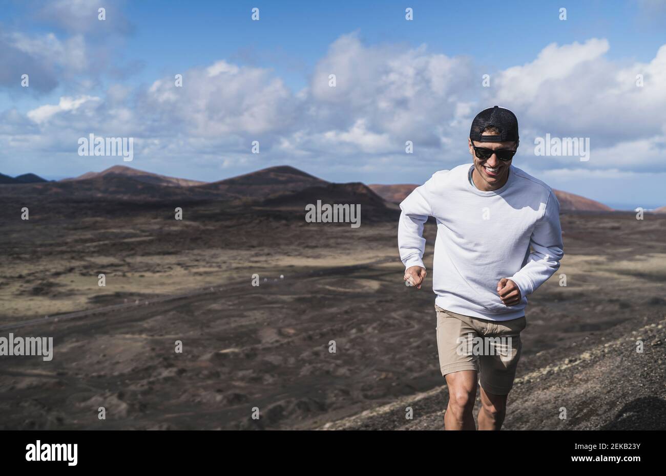 Joyeux touriste mâle courant sur le volcan El Cuervo pendant les vacances, Lanzarote, Espagne Banque D'Images
