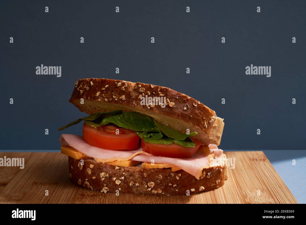 Sandwich au jambon sur la planche à découper contre le mur à l'intérieur Banque D'Images