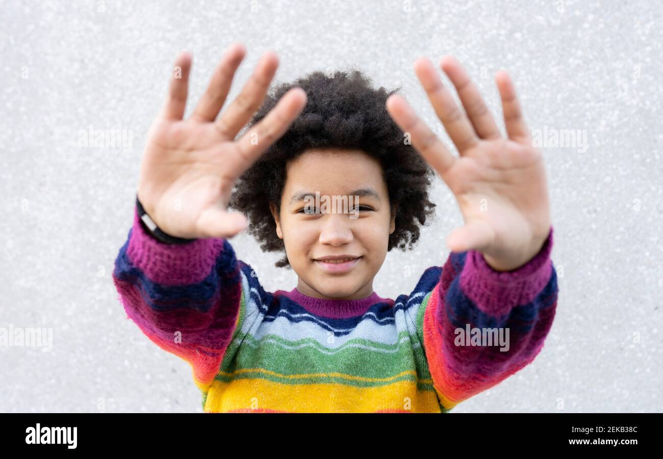 Fille souriante gestante signe d'arrêt de main tout en se tenant contre le mur Banque D'Images