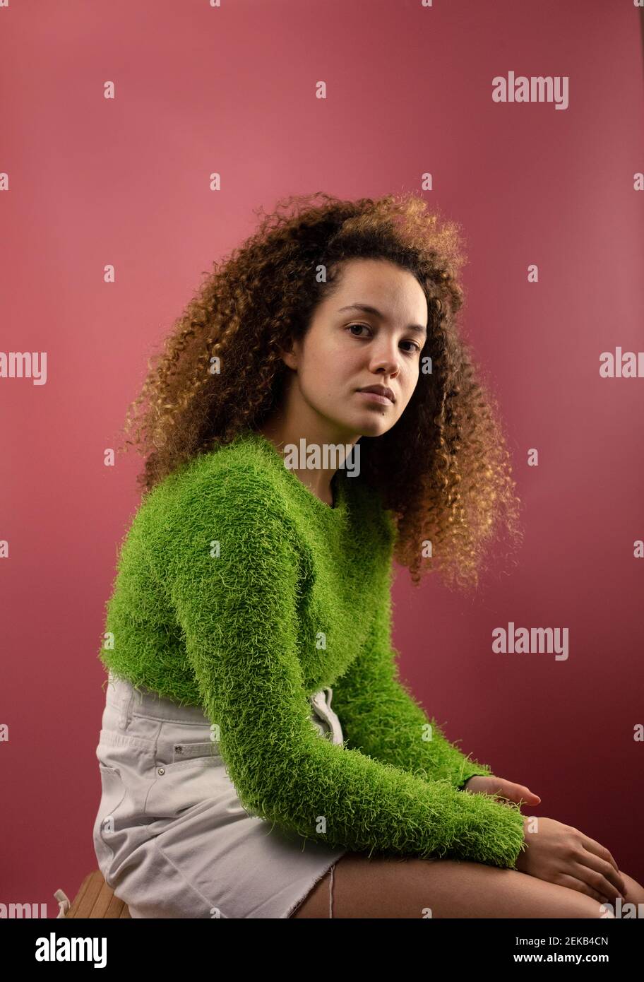 Femme à la mode avec expression blanche assise par un fond de couleur corail Banque D'Images