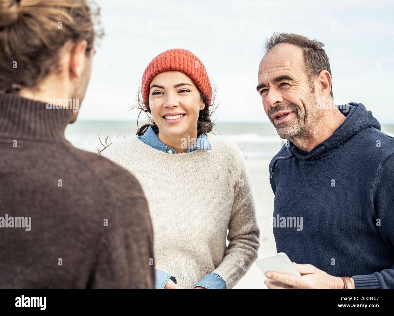 Trois personnes parlent à la plage Banque D'Images