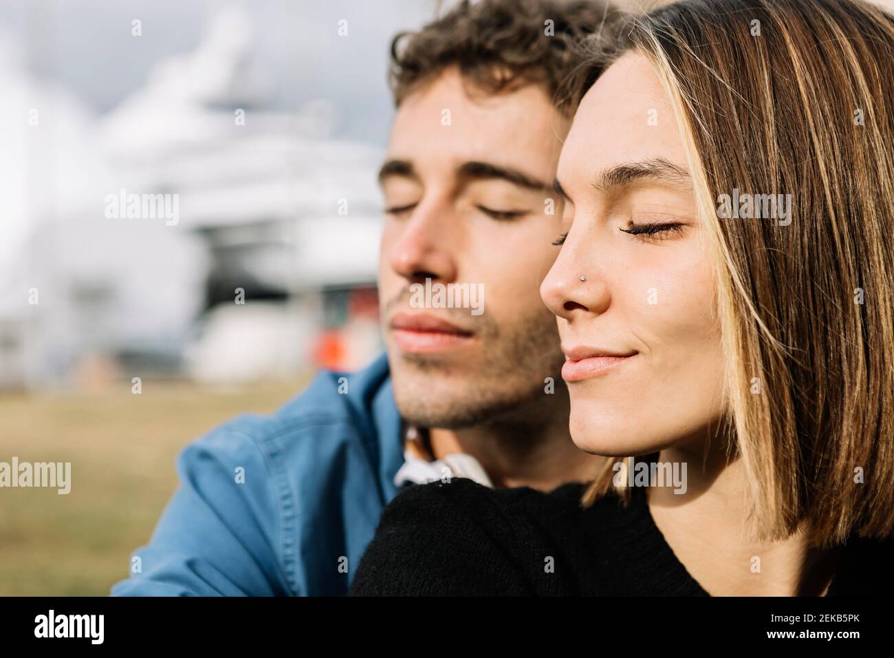 Jeune couple avec les yeux fermés à l'extérieur Banque D'Images