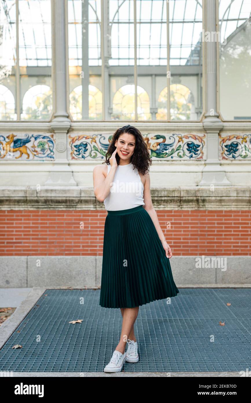 Femme souriante portant le haut et la jupe posant tout en se tenant contre  serre Photo Stock - Alamy