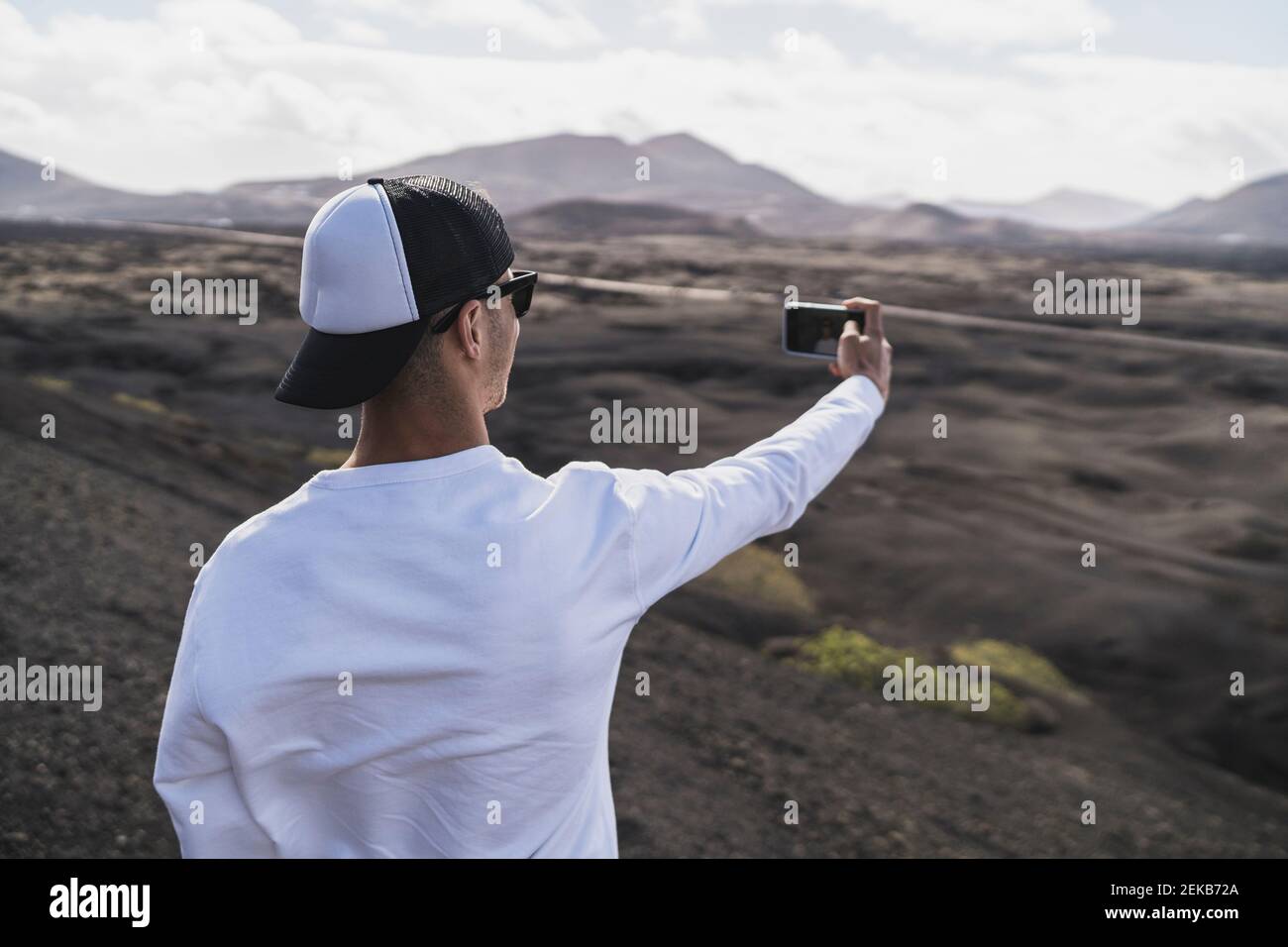 Mâle touriste en chapeau prenant selfie au volcan El Cuervo pendant les vacances, Lanzarote, Espagne Banque D'Images