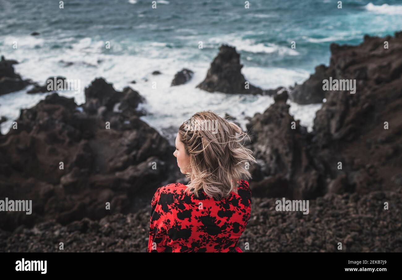 Jeune femme regardant la vue sur la mer en se tenant à Los Hervideros, Lanzarote, Espagne Banque D'Images