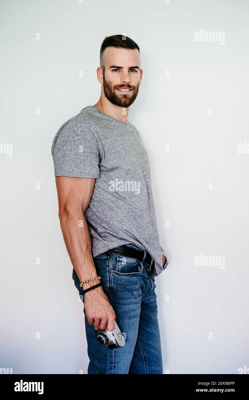 Jeune homme souriant tenant un appareil photo vintage Banque D'Images