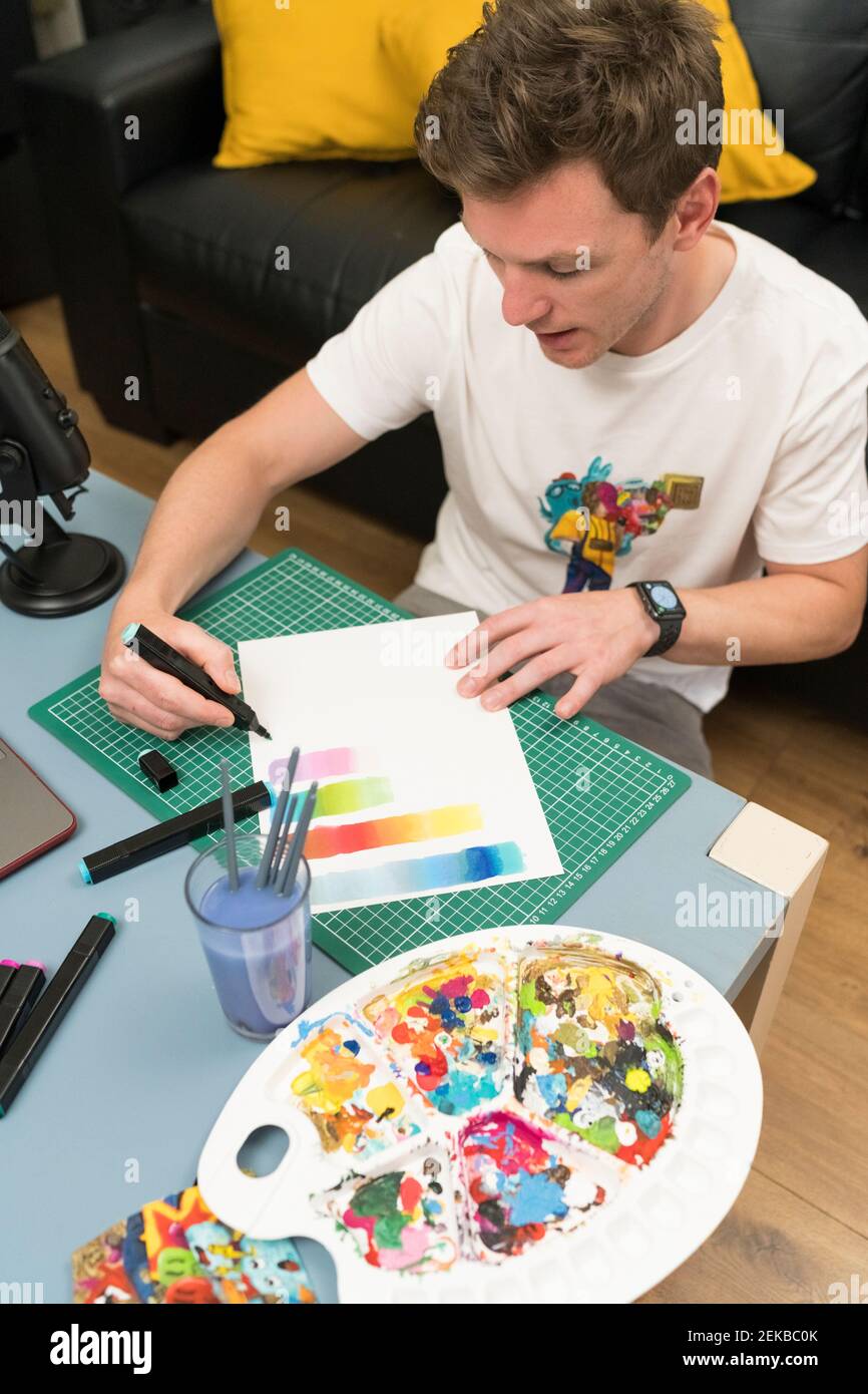 Artiste masculin montrant un dégradé de couleurs à travers un stylo à colorier en direct diffusion à domicile Banque D'Images
