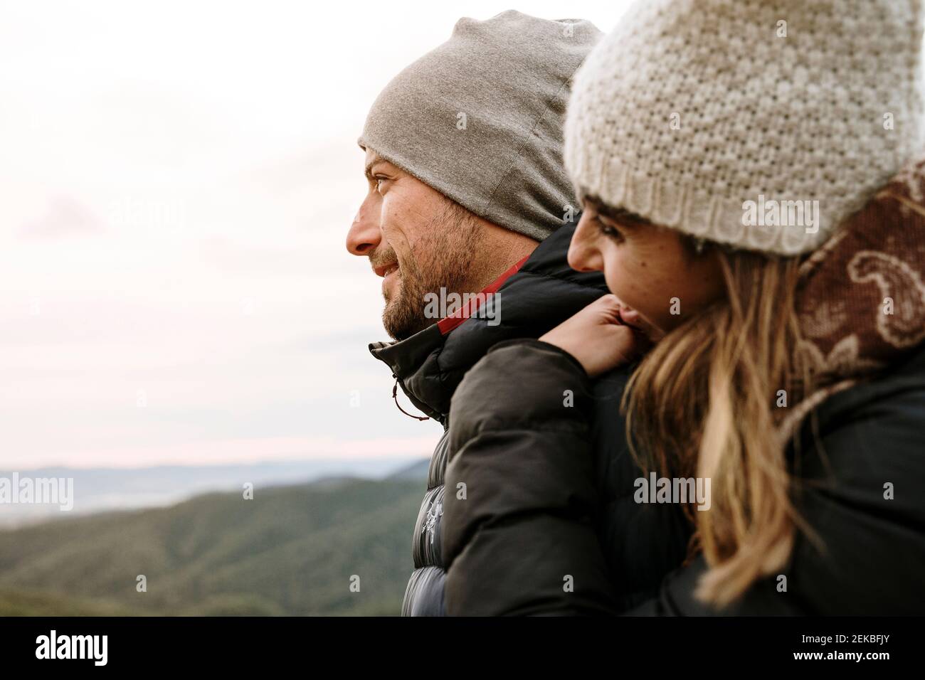 Couple souriant dans des vêtements chauds regardant loin pendant l'hiver Banque D'Images