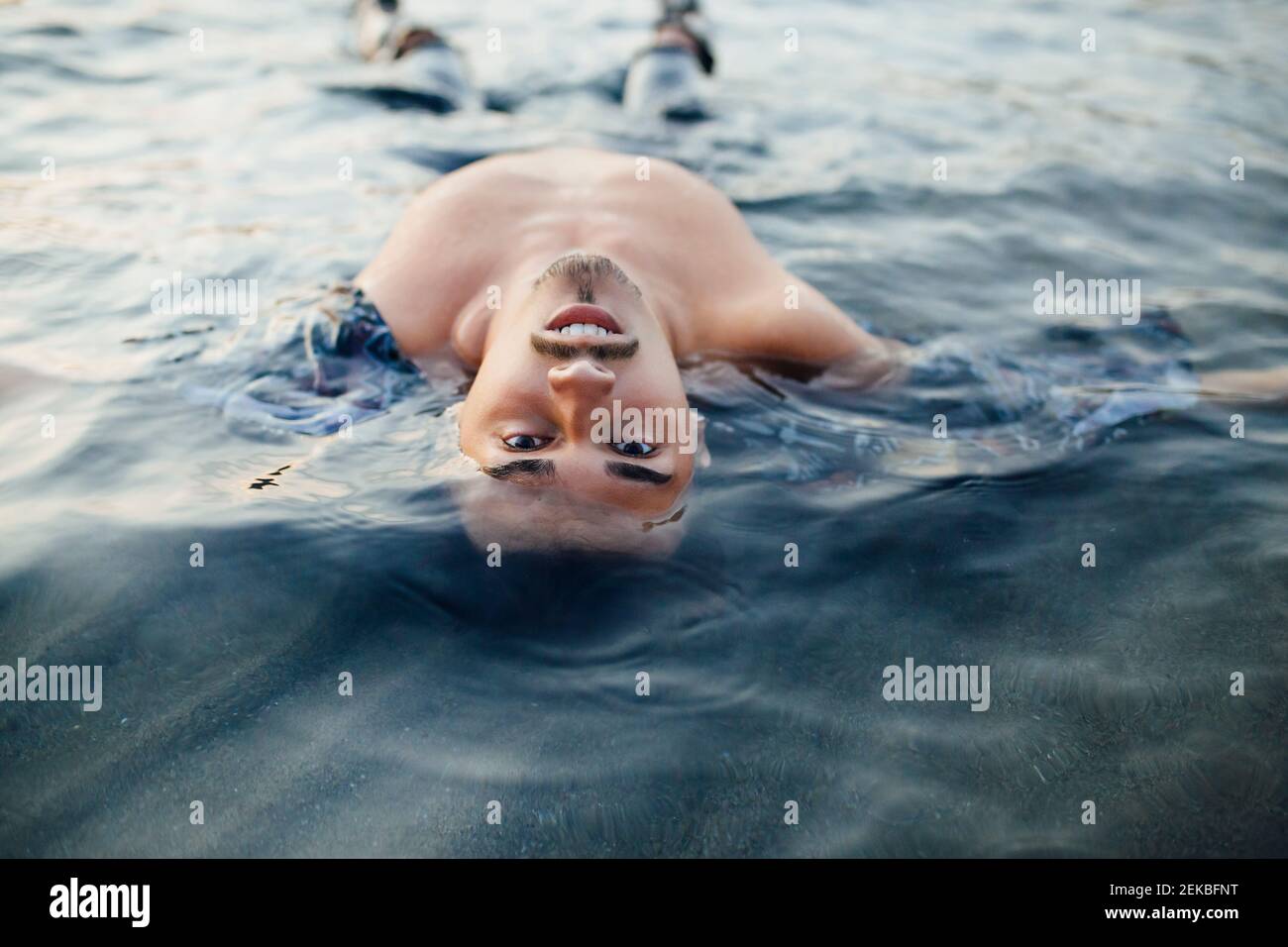 Jeune homme floating in water Banque D'Images