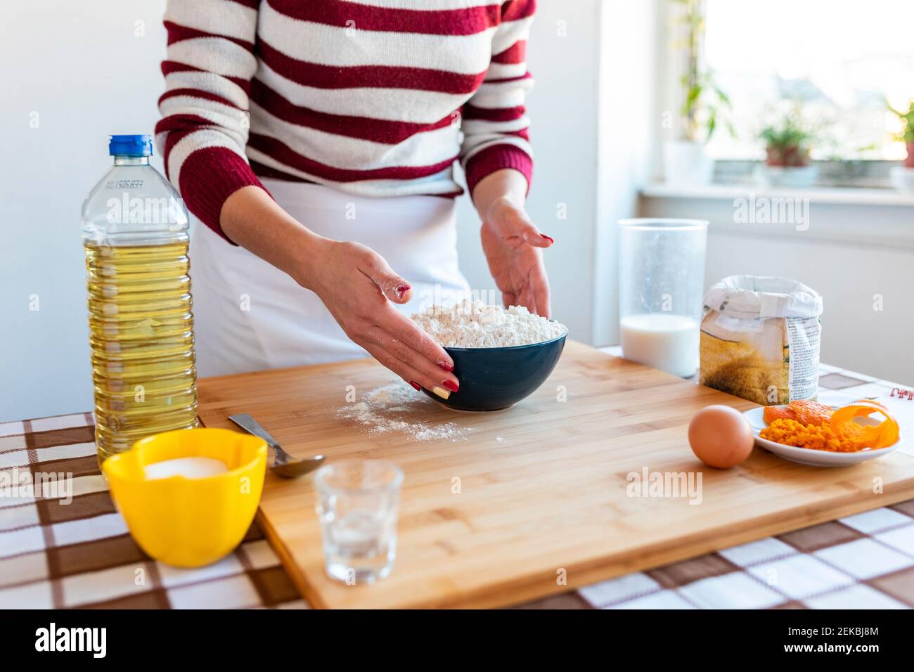 Femme avec bol à farine sur planche à découper dans la cuisine à accueil Banque D'Images