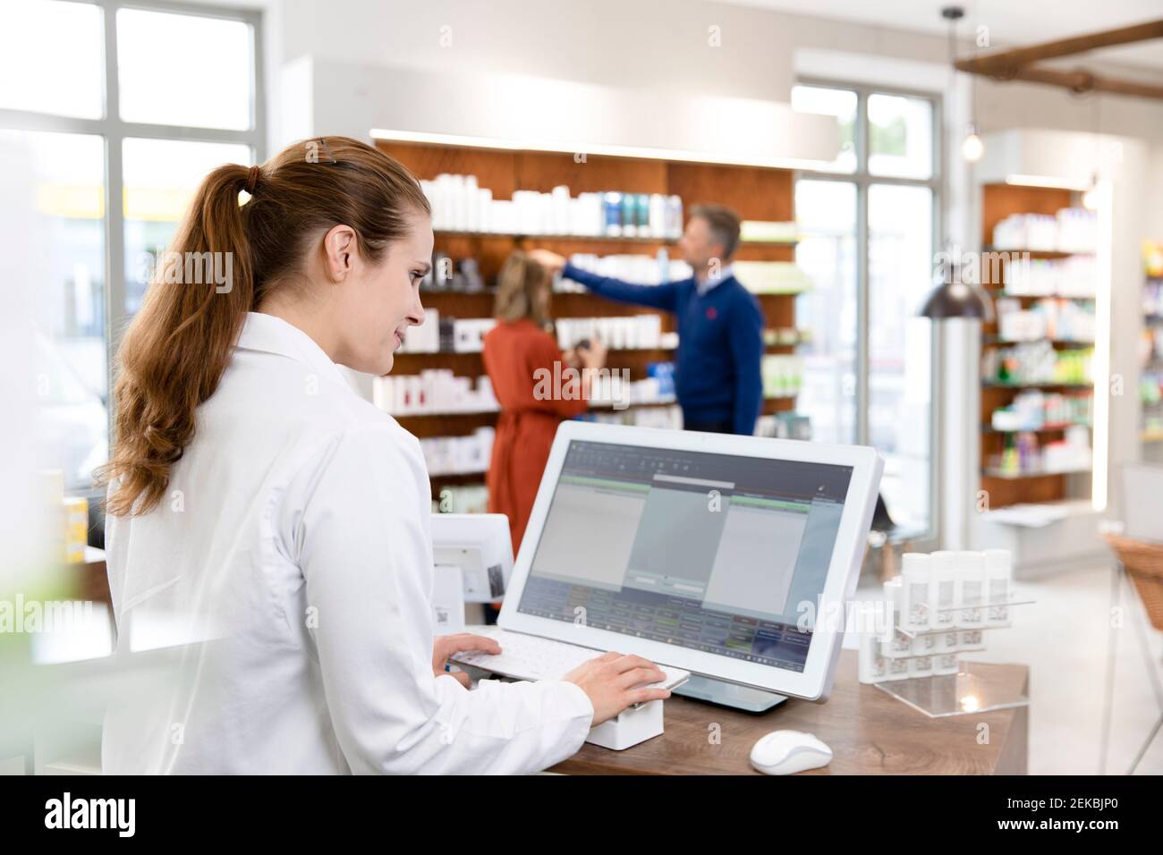 Une pharmacien féminine utilise un ordinateur à la caisse du magasin Banque D'Images