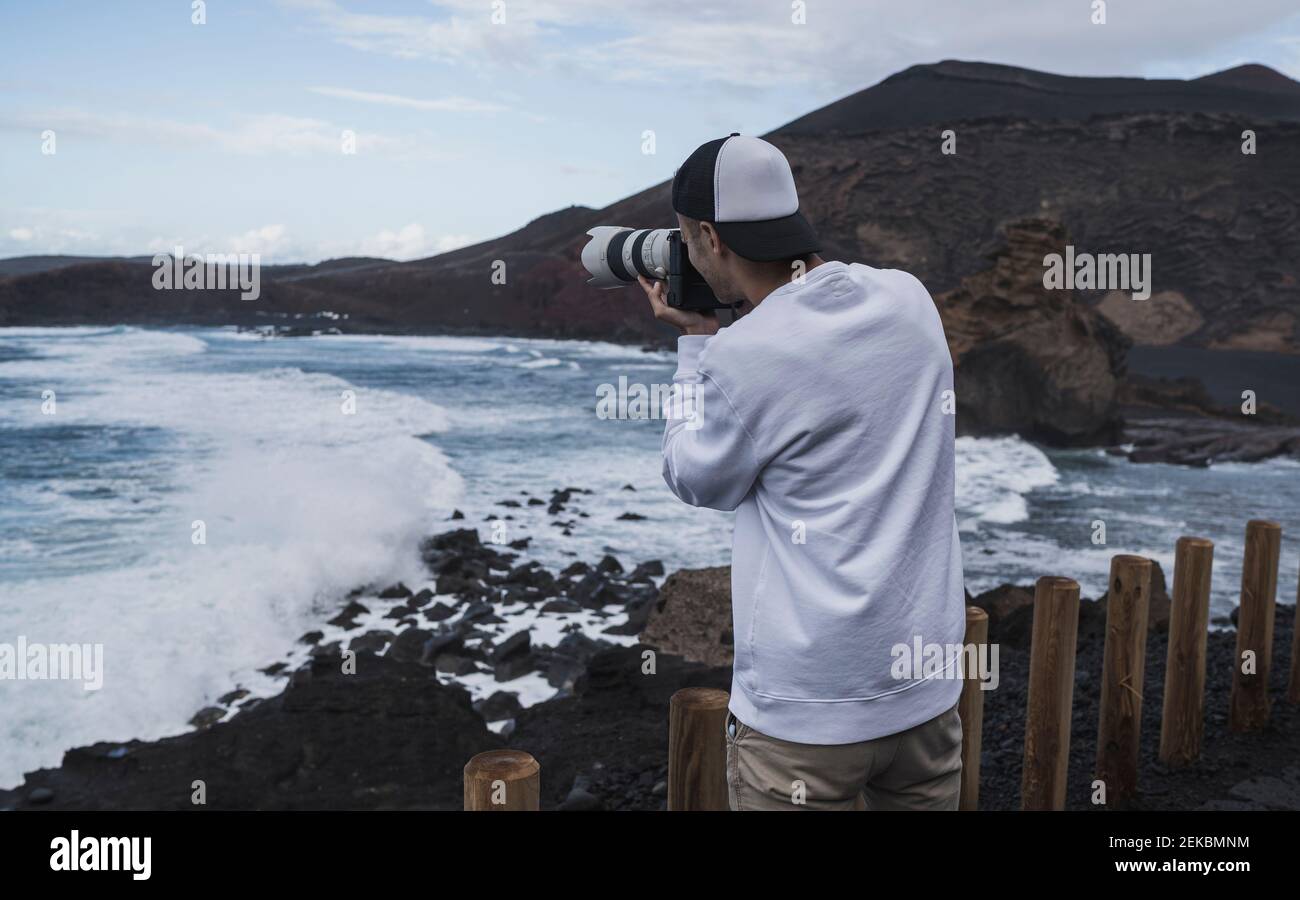 Jeune touriste mâle photographiant la mer à El golfo pendant les vacances, Lanzarote, Espagne Banque D'Images
