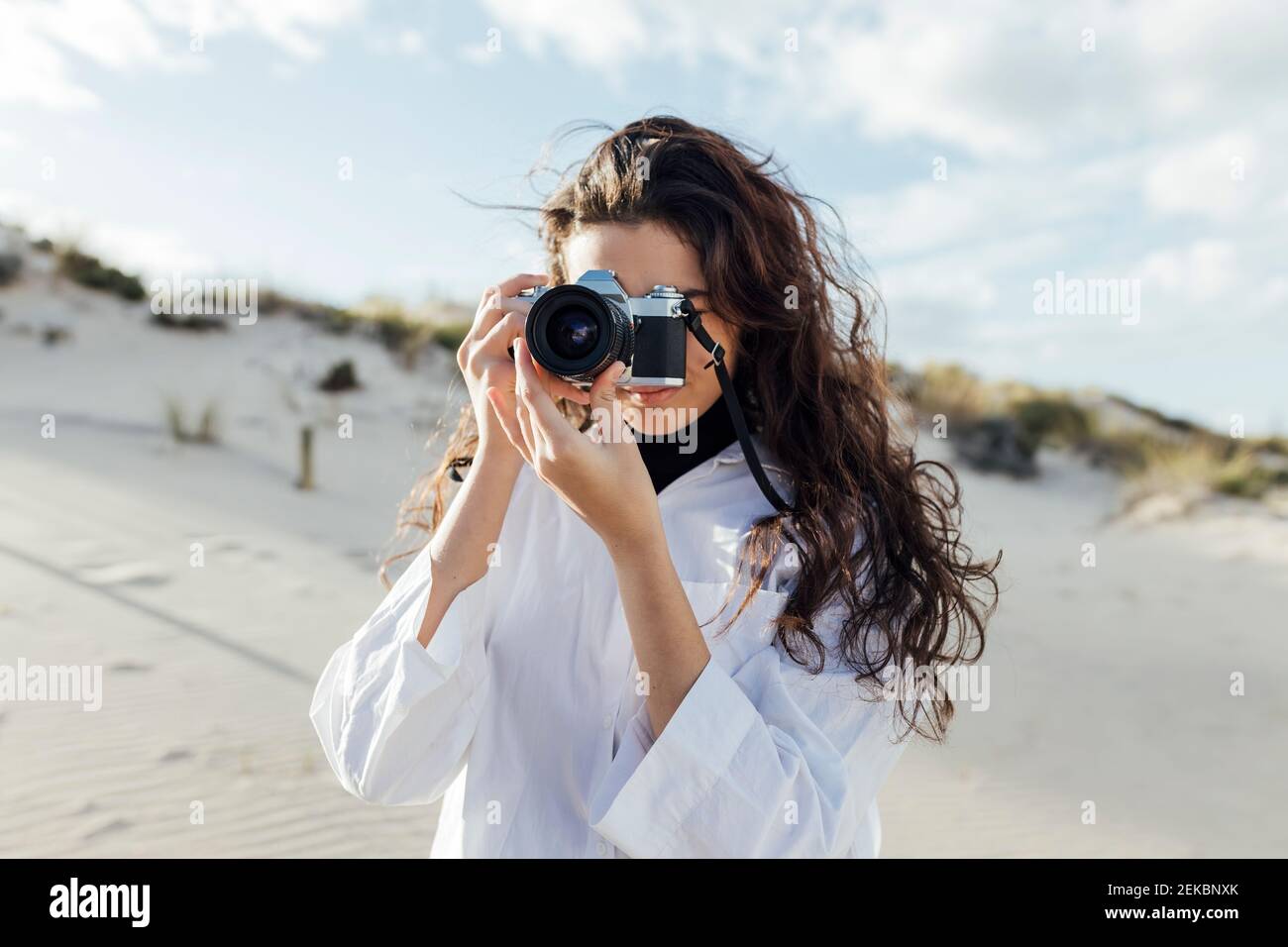 Jeune femme photographiant à travers un appareil photo d'époque sur les dunes de sable Banque D'Images