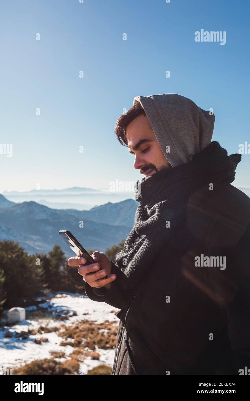 Portrait d'un homme envoyant un message avec son smartphone dans la neige Banque D'Images