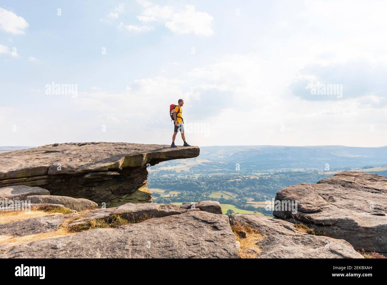 Jeune randonneur mâle regardant la vue en se tenant debout sur le dessus de montagne pendant la journée ensoleillée Banque D'Images
