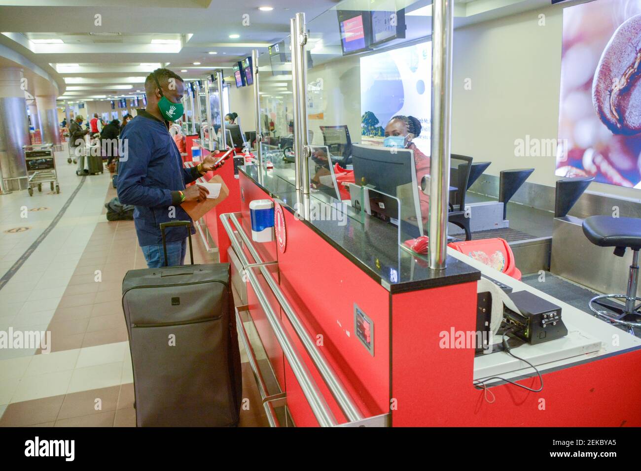 Un employé de Kenya Airways s'enregistre auprès d'un passager portant un  masque facial à l'aéroport international Jomo Kenyatta de Nairobi. Kenya  Airways a repris ses vols internationaux à la suite de l'assouplissement