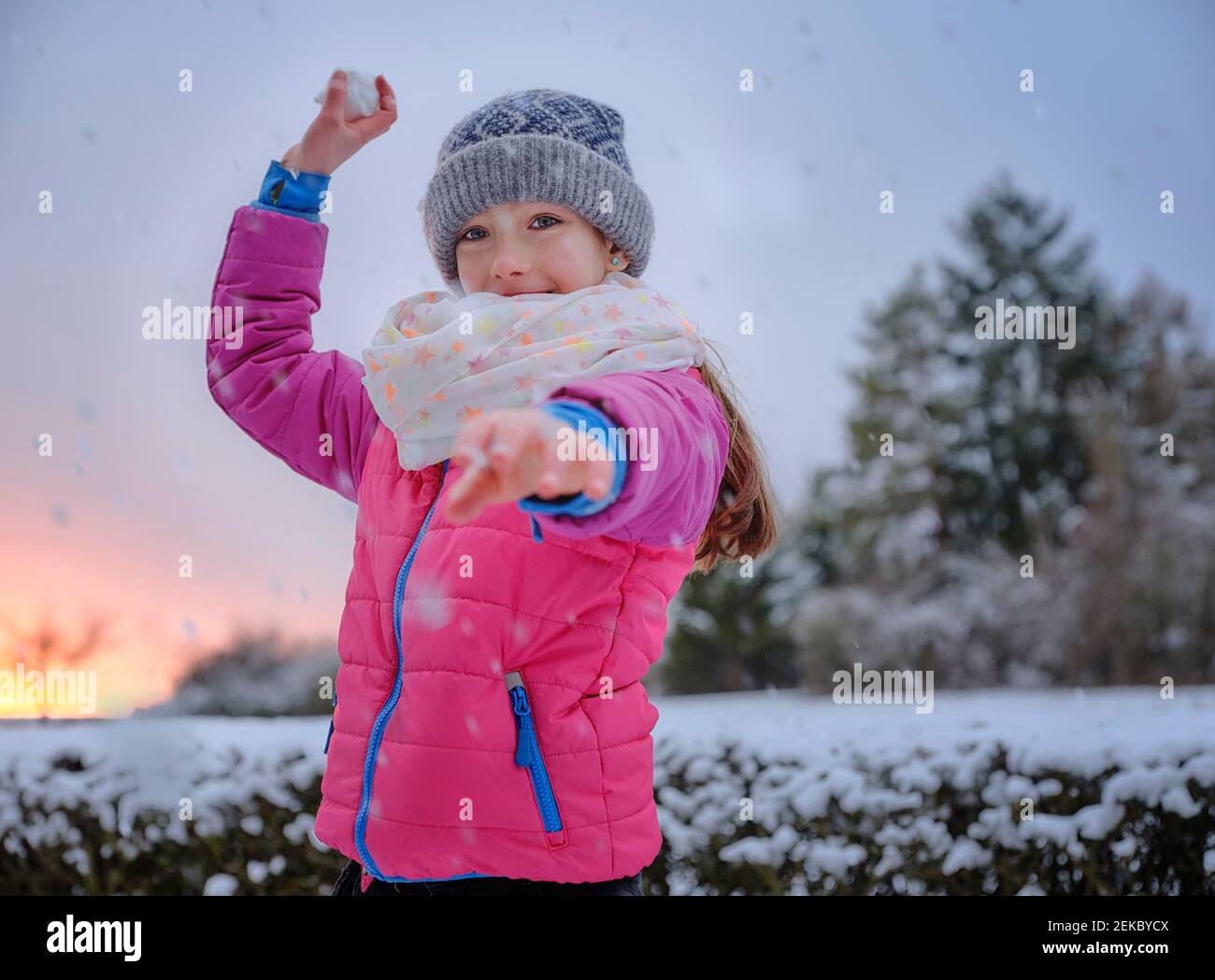 Une fille joueuse jette un ballon de neige dans la neige pendant l'hiver Banque D'Images