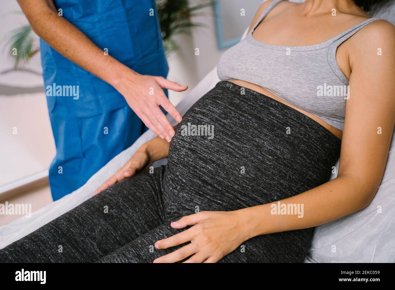 Sage-femme examinant l'abdomen de la femme enceinte Banque D'Images