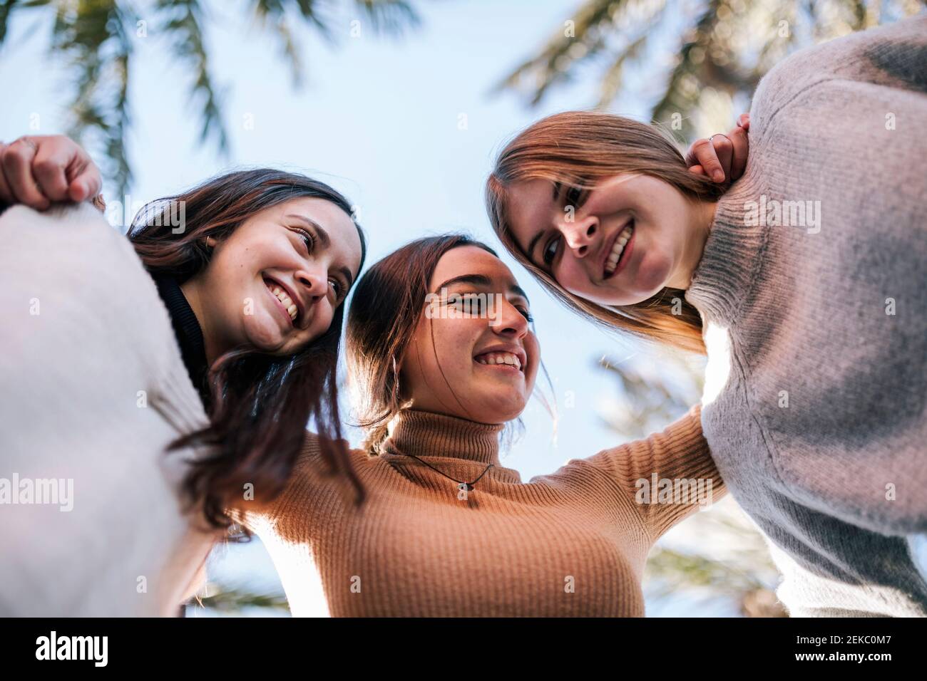 Des amies souriantes se mêlent au ciel dégagé dans le parc Banque D'Images