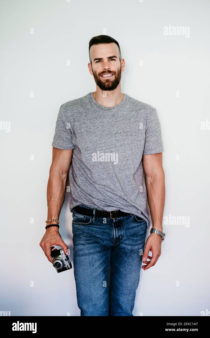 Jeune homme souriant tenant un appareil photo vintage Banque D'Images