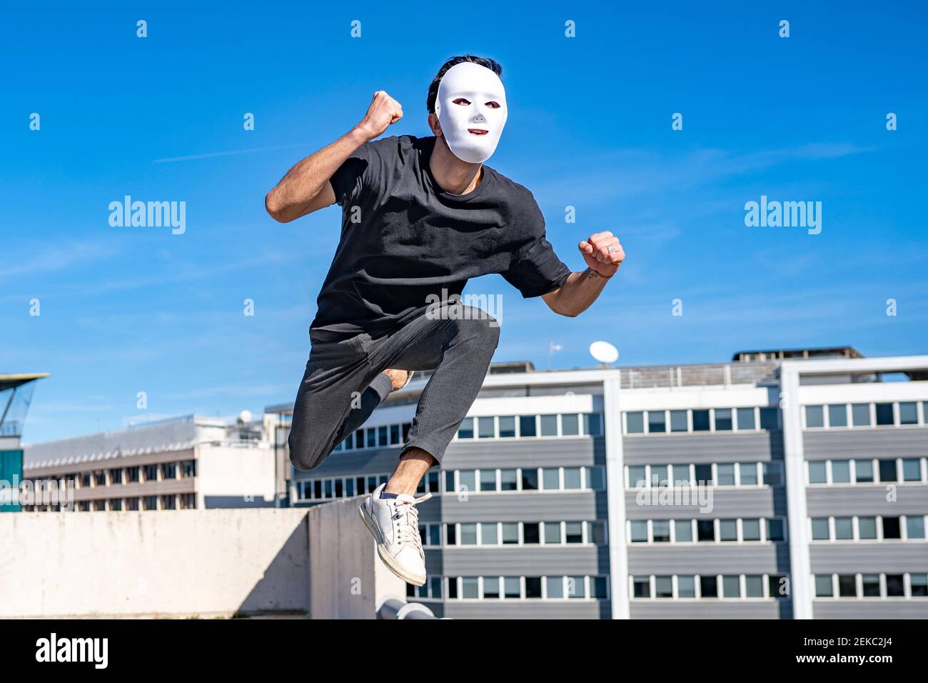 Jeune homme portant un masque blanc courant contre le ciel Banque D'Images