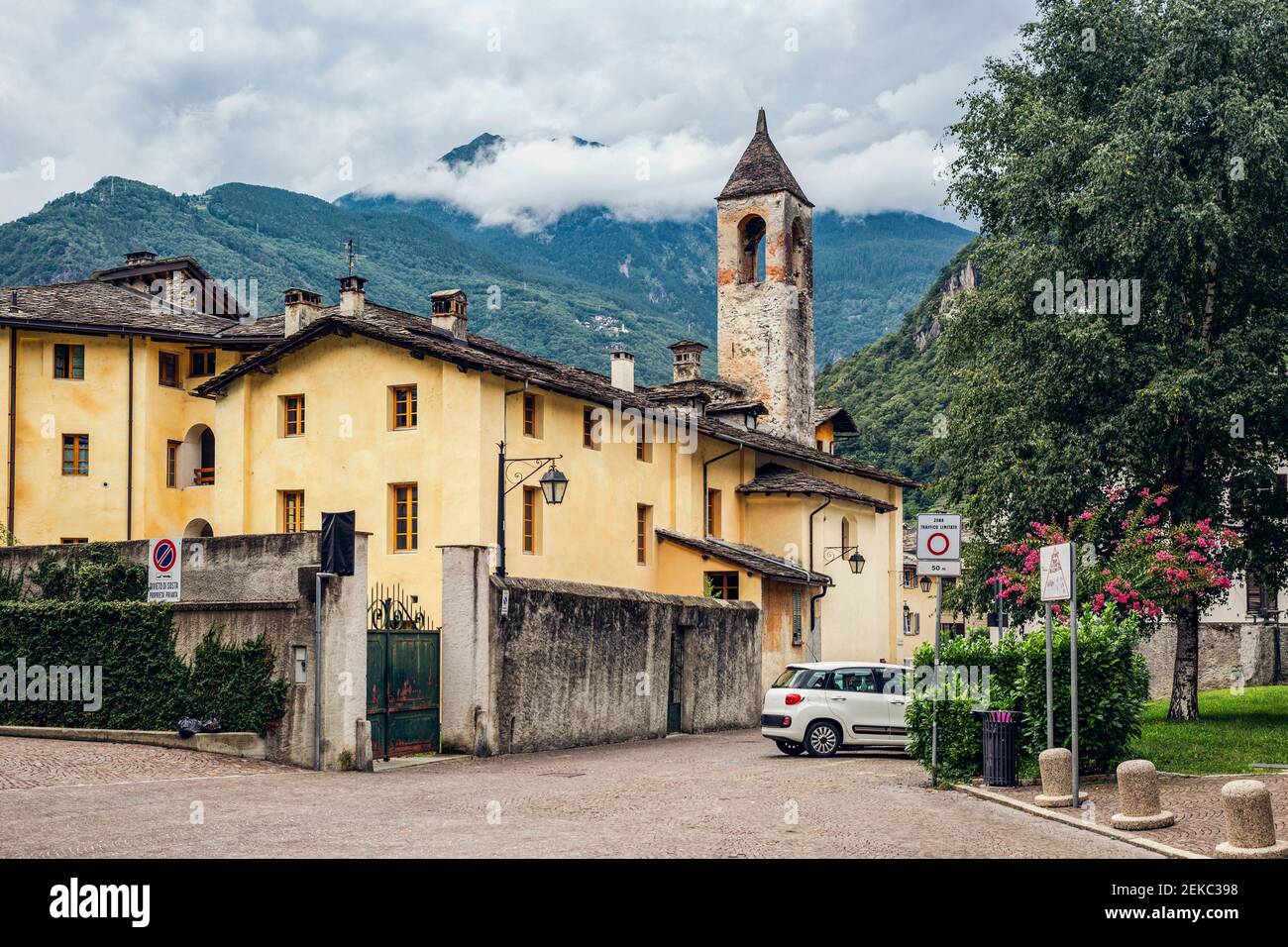 Clocher par arbre en ville contre la chaîne de montagnes, Valchiavenna, Chiavenna, province de Sondrio, Lombardie, Italie Banque D'Images