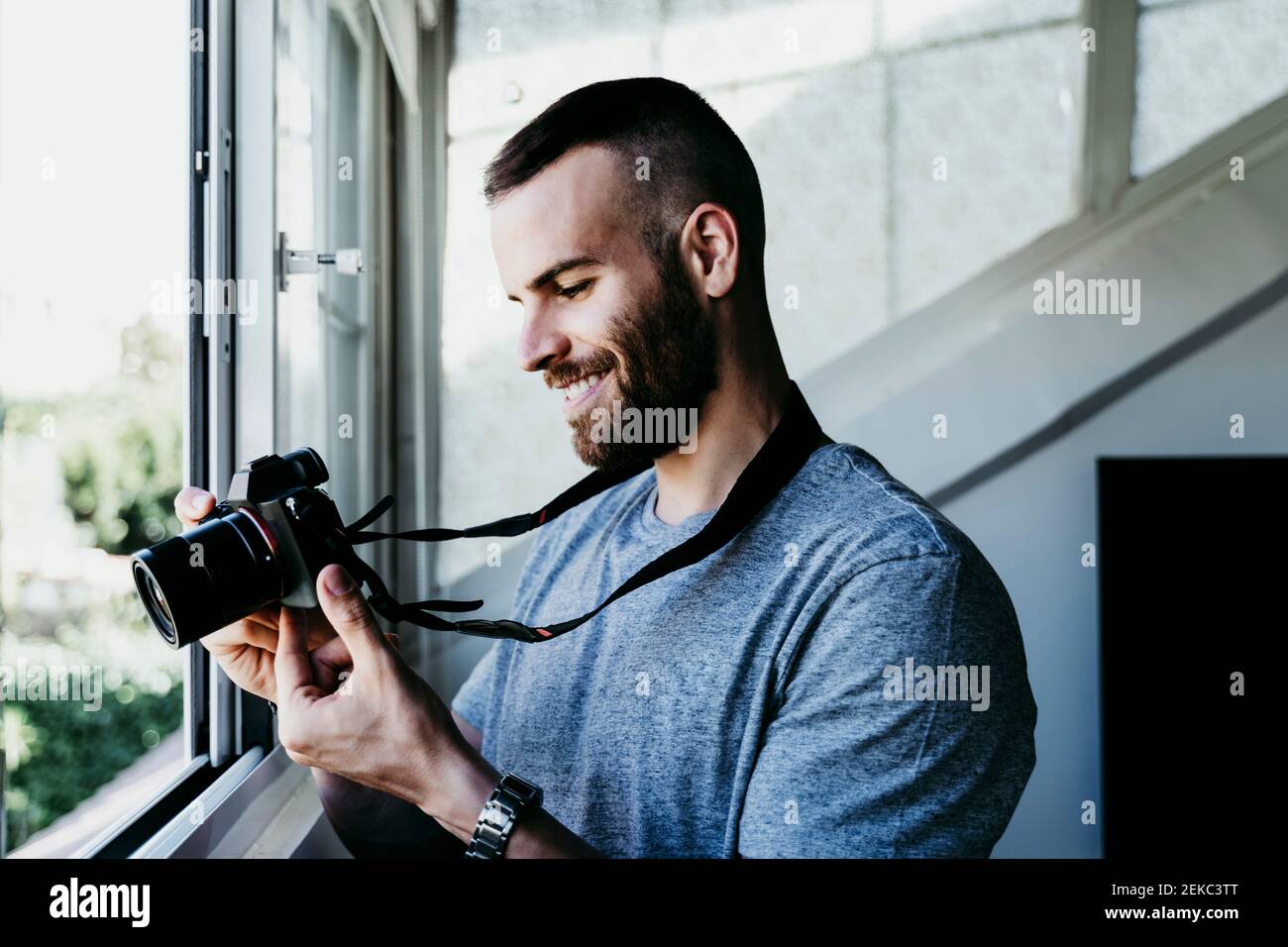 Homme souriant travaillant avec l'appareil photo à la maison Banque D'Images