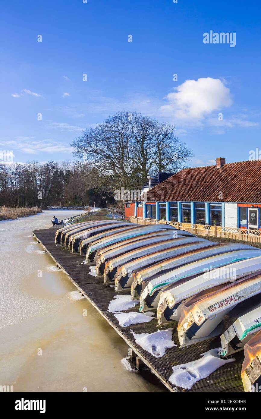 Petits bateaux à rames sur la jetée de la rivière gelée à Paterswolde, pays-Bas Banque D'Images