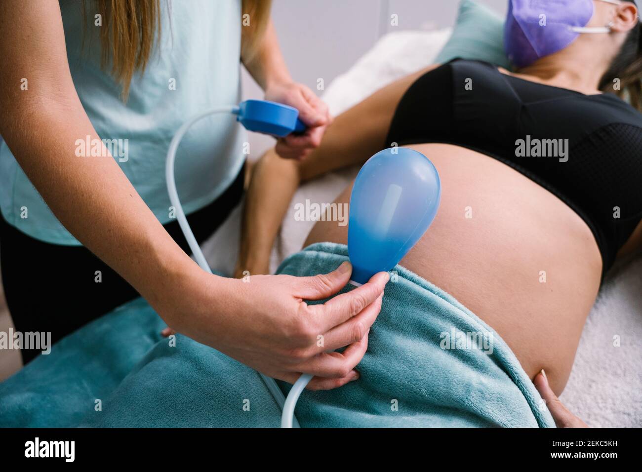 Sage-femme tenant un ballon bleu contre l'abdomen de la femme enceinte Banque D'Images