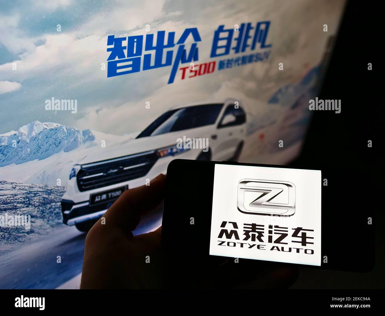 Personne tenant le téléphone portable avec le logo d'affaires du fabricant automobile chinois Zotye Auto sur l'écran en face de la page Web. Mise au point sur l'affichage du téléphone. Banque D'Images