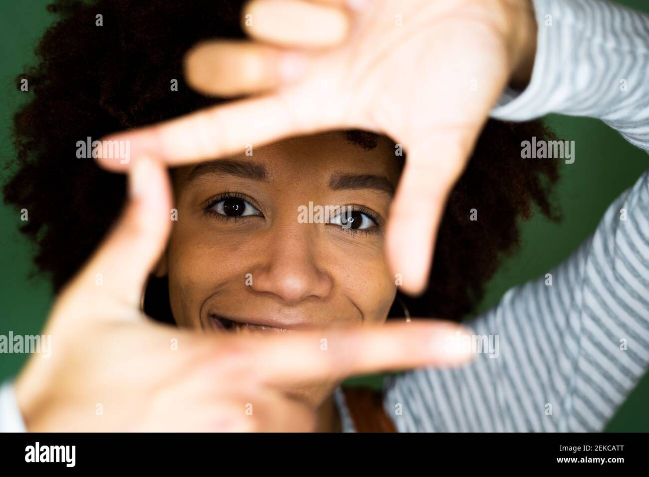 Jeune femme afro regardant à travers le cadre de doigt Banque D'Images