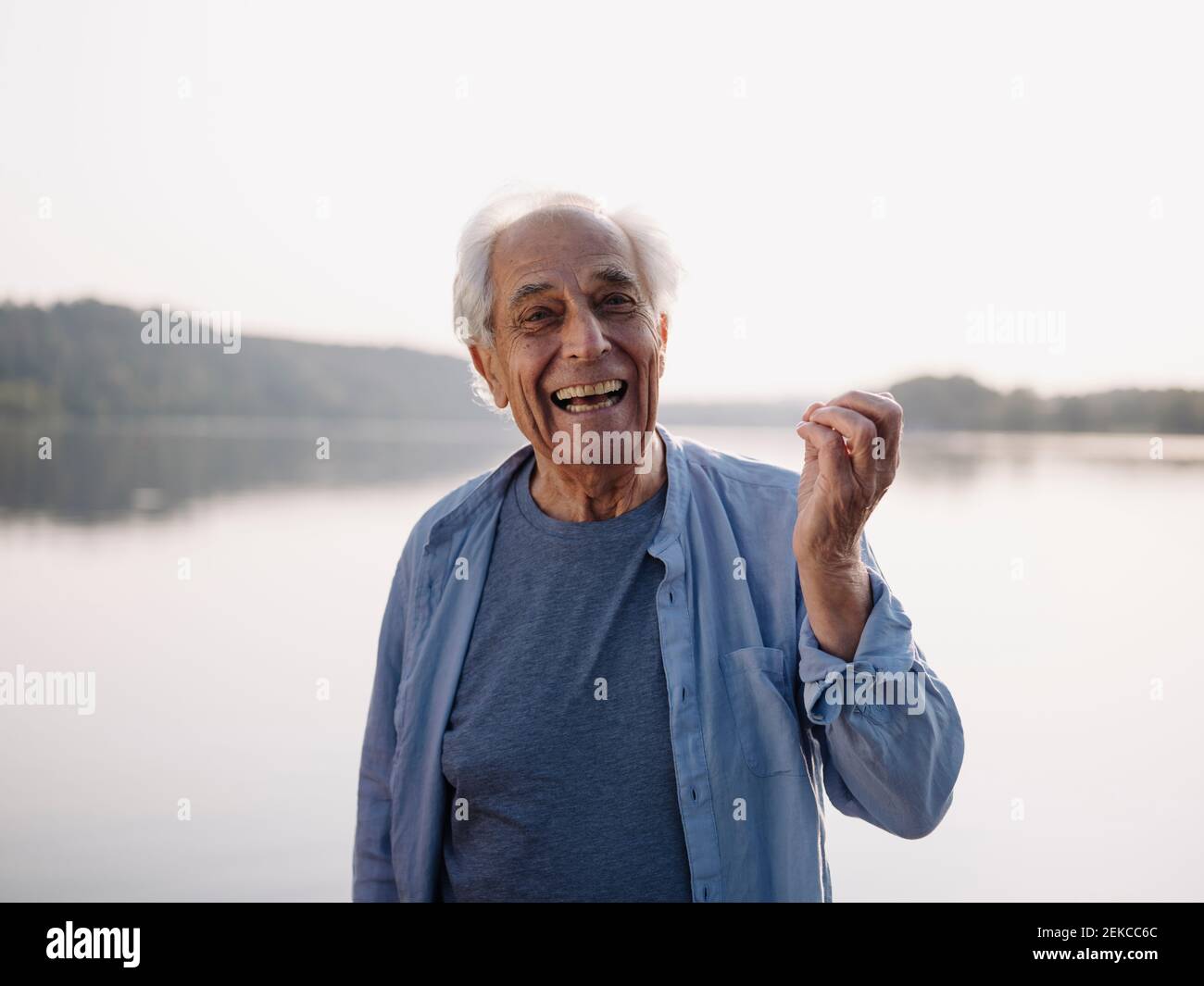Un homme heureux chantant en se tenant contre le lac Banque D'Images
