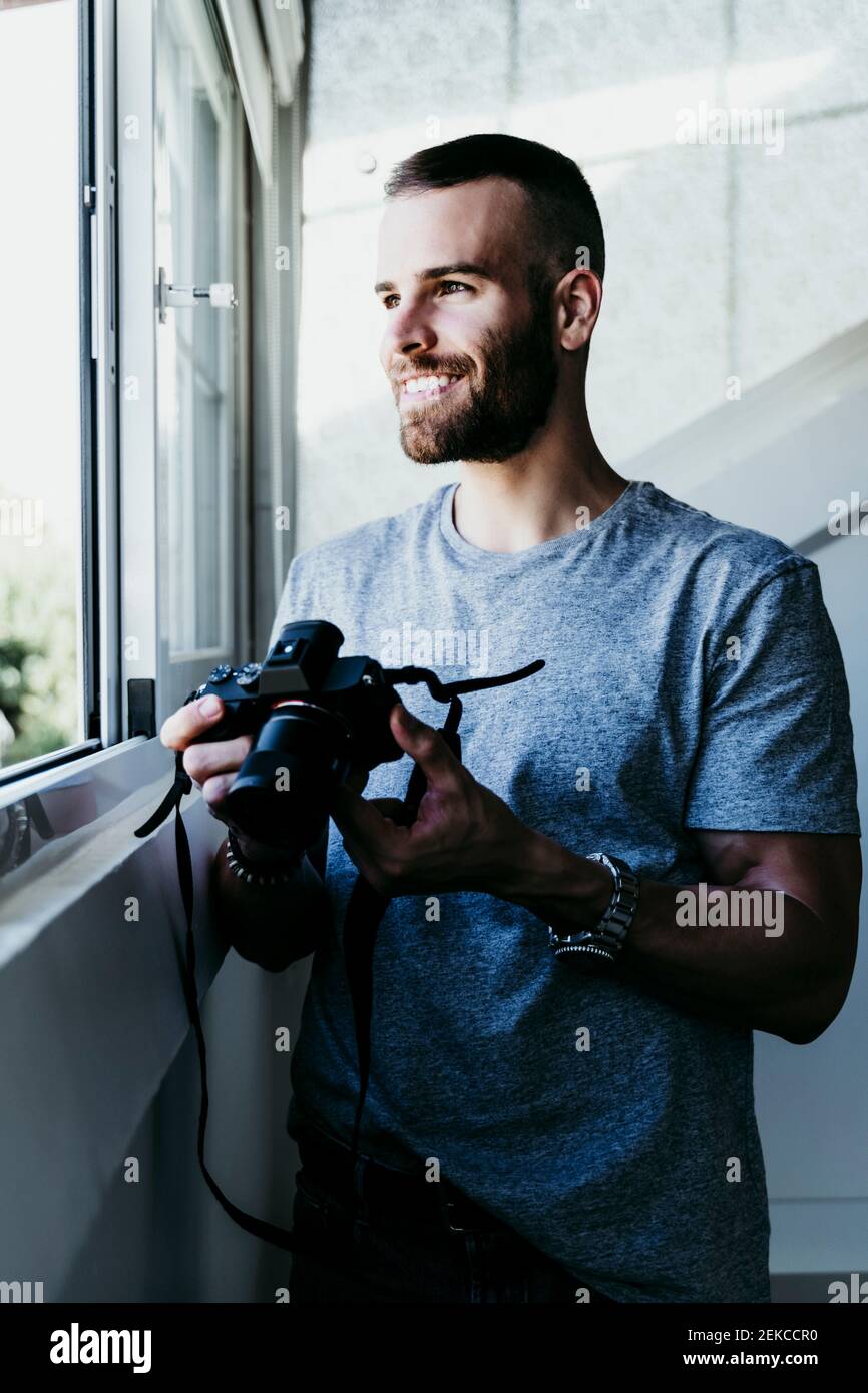 Homme souriant travaillant avec l'appareil photo à la maison Banque D'Images