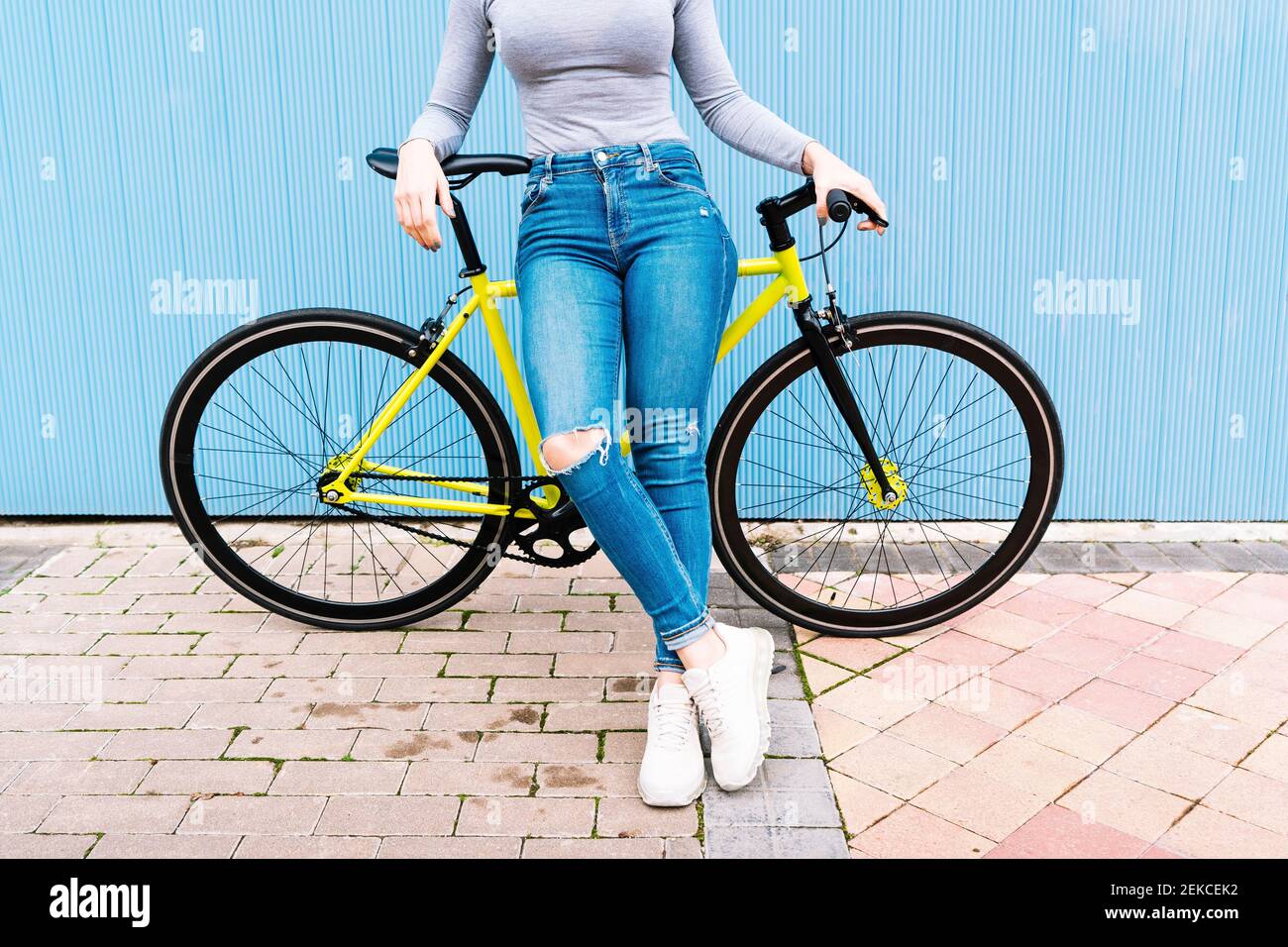 Femme adulte de taille moyenne portant un Jean déchiré assis sur un vélo  fixe contre le mur bleu Photo Stock - Alamy
