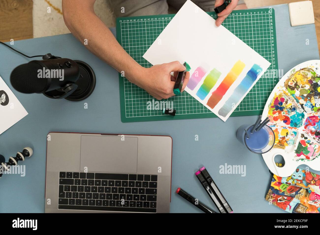 Artiste montrant un dégradé de couleurs avec un stylo à colorier sur du papier pendant diffusion en direct sur un ordinateur portable à la maison Banque D'Images