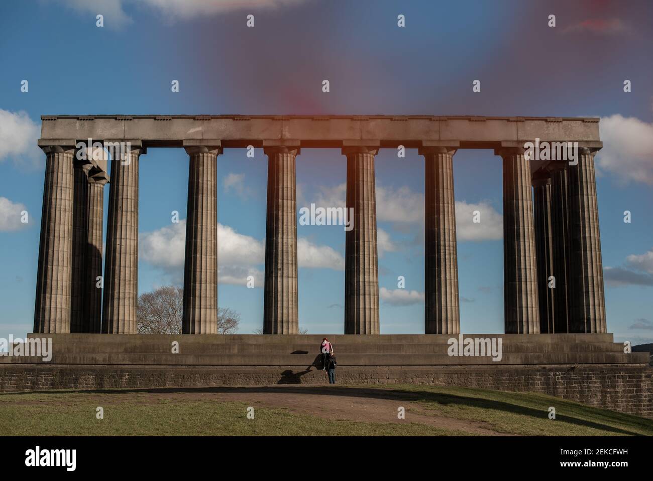 Couple solitaire sur les marches du monument national écossais sur Calton Hill, Édimbourg lors d'une journée ensoleillée pendant l'enfermement 2021 Banque D'Images