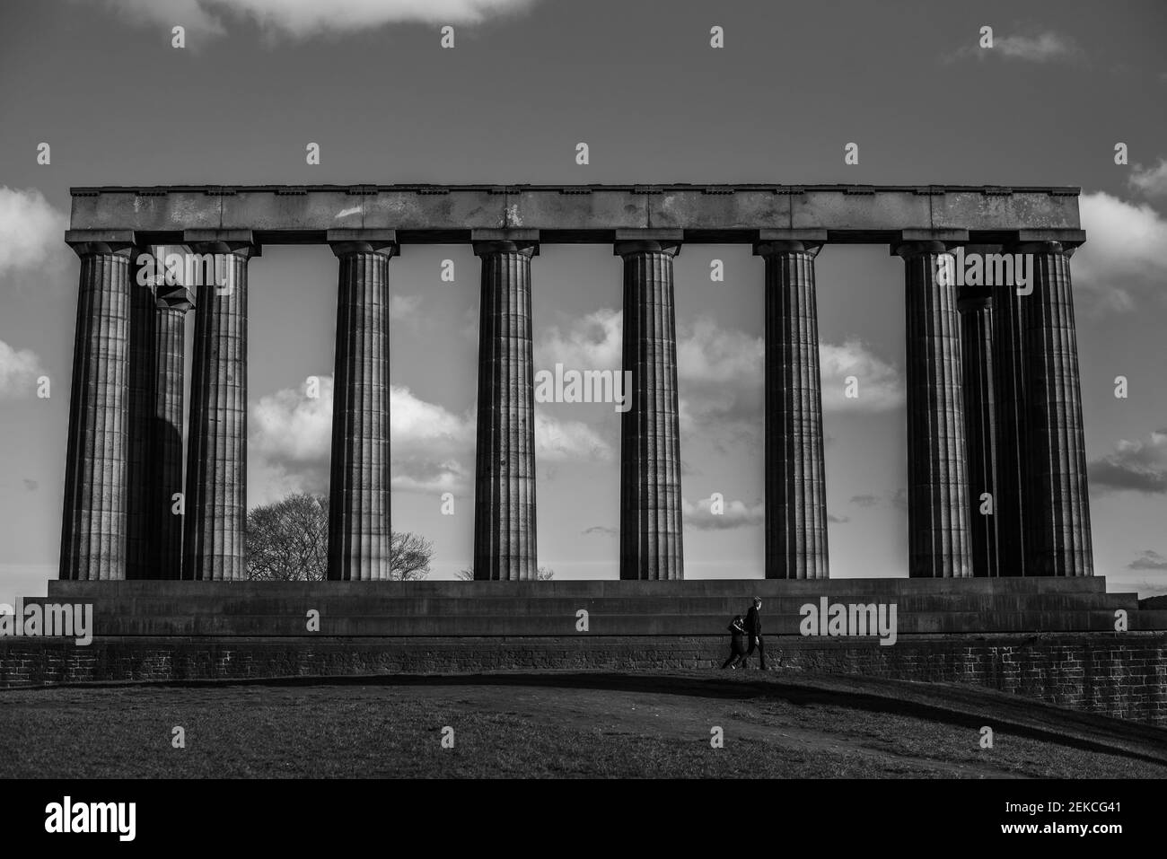 Couple solitaire sur les marches du monument national écossais sur Calton Hill, Édimbourg lors d'une journée ensoleillée pendant l'enfermement 2021. Prise de vue en noir et blanc spectaculaire Banque D'Images