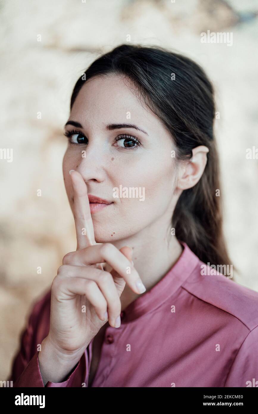 Femme d'affaires avec le doigt sur les lèvres au café Banque D'Images