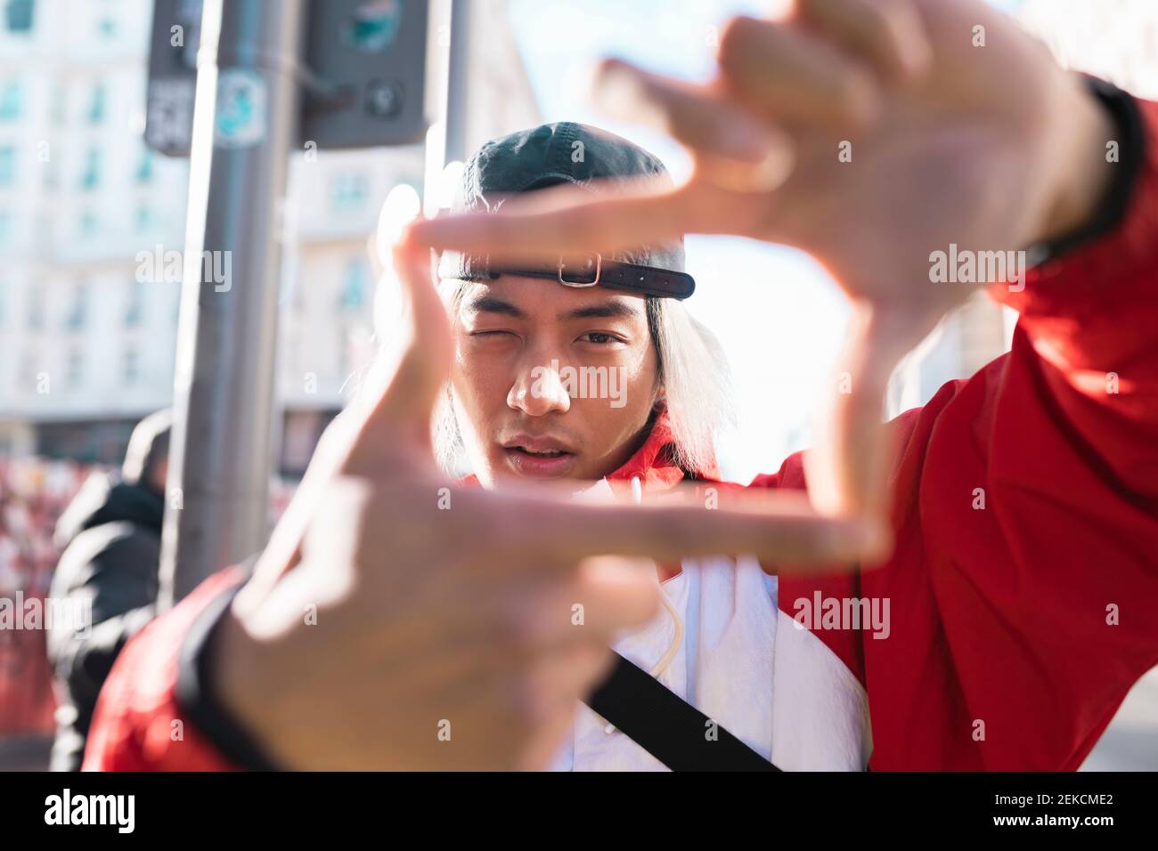 Jeune homme formant un cadre de doigt à l'extérieur Banque D'Images