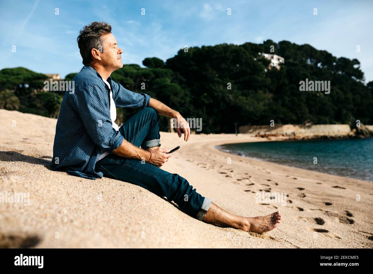 Homme avec les yeux fermés se détendant à la plage Banque D'Images