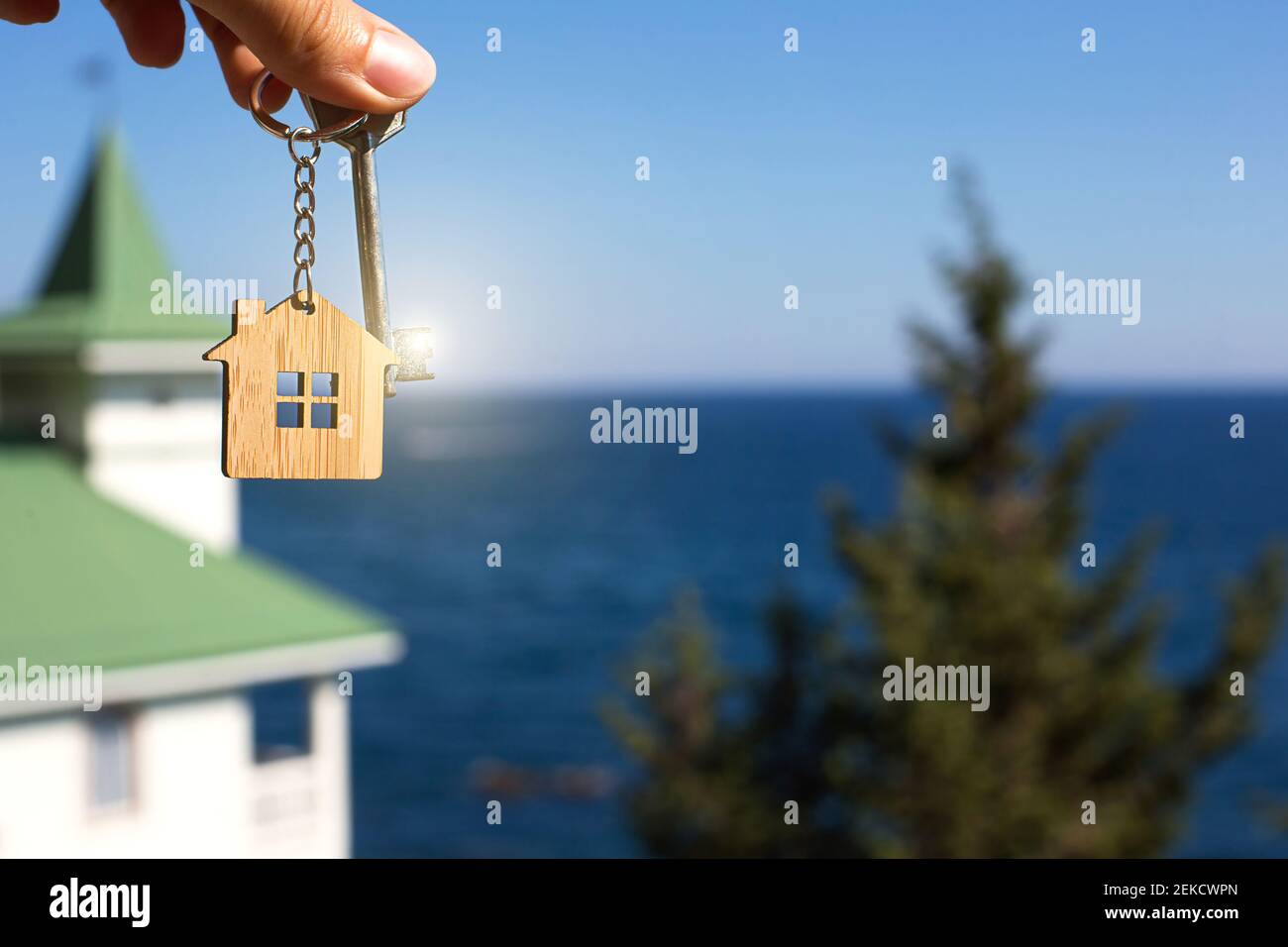 Pendentif en bois d'une maison et clé. Fond de mer, sapin et chalet. Maison et vie sur l'océan, construction, projet, déménagement à la nouvelle maison, mortg Banque D'Images